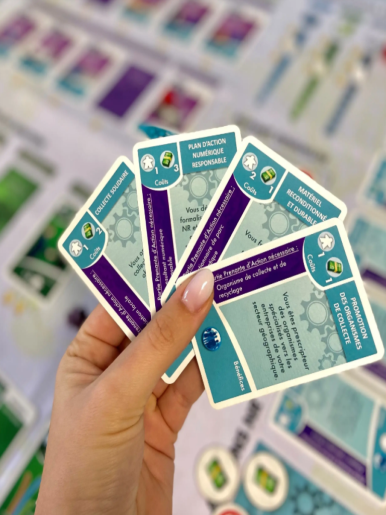 Jeu de carte sur le numérique responsable exposé en forme d'éventail, avec en fond un plateau de jeu