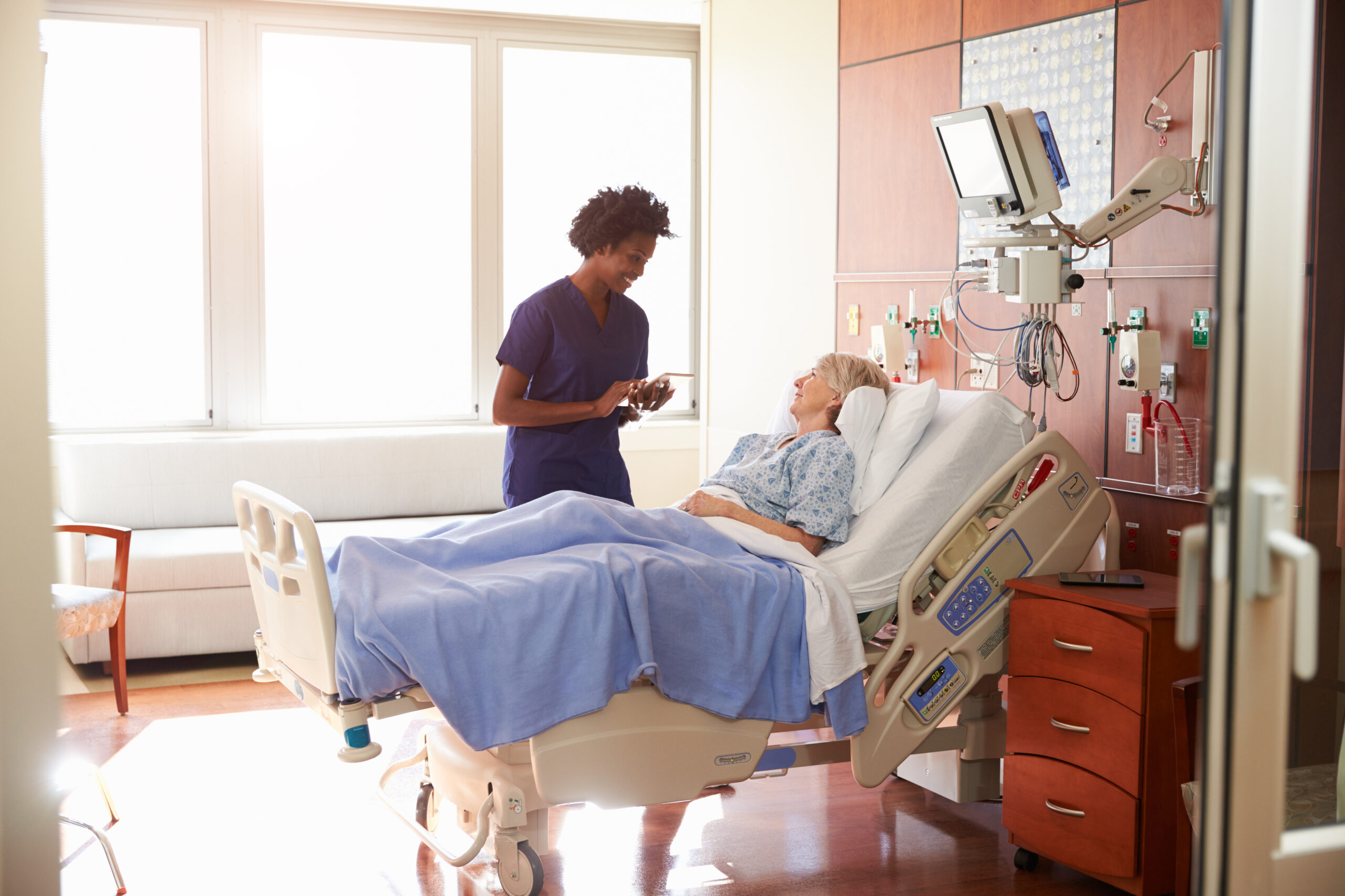 Il s'agit d'un patient allongé sur un lit d'hôpital accompagné par un professionnel de santé.